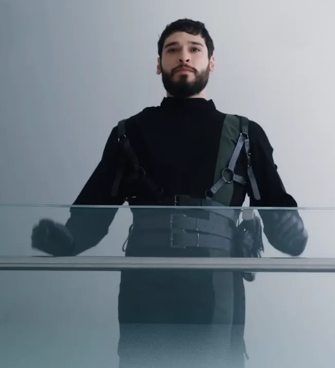 A man wearing a black outfit similar to a futuristic military commander outfit but with many leather straps.